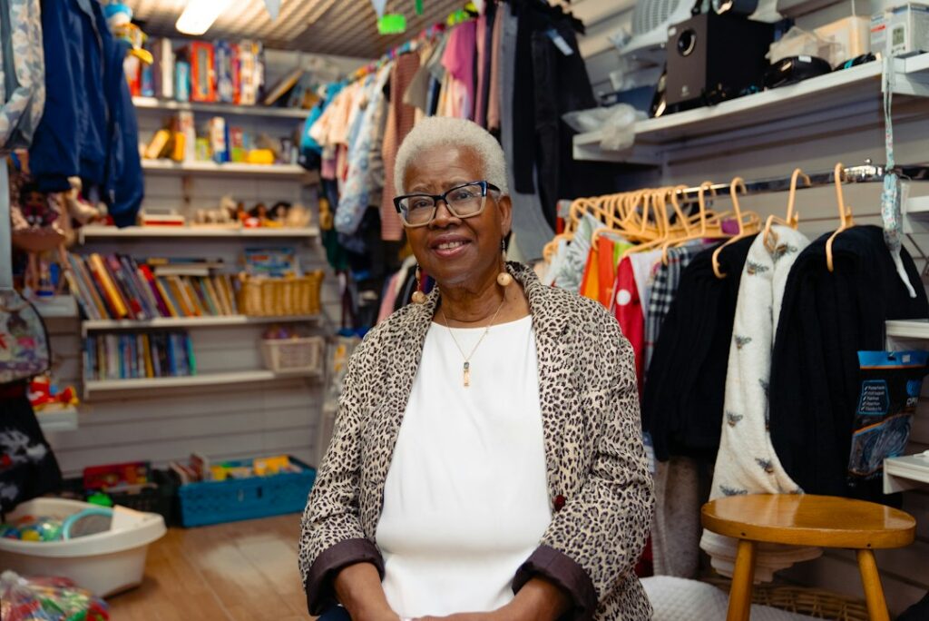 An older woman smiling in her clothing shop