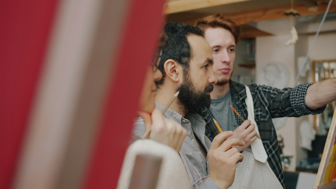 A male art teacher working with students in a creative studio; representative stock photography